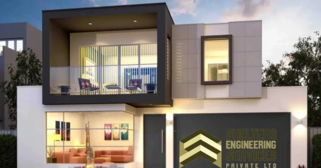 Modern residential building with a grey and white facade, featuring a prominent balcony on the upper level and large windows. The ground floor has a brightly lit interior with a red sofa and artwork. A company logo for "SHELTRES ENGINEERING SERVICES PRIVATE LTD" is visible on the exterior wall.