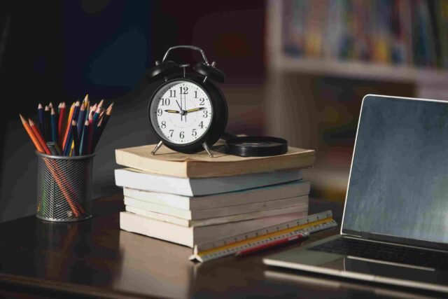 A book, laptop, clock and stationary